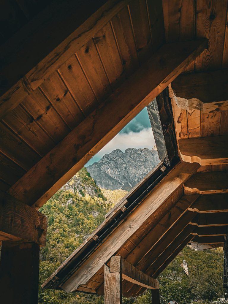 View of a mountain framed by a rustic wooden cabin roof. Tranquil and scenic.